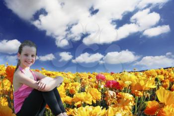 Charming beautiful six year old girl posing in a field of blooming yellow and red buttercups