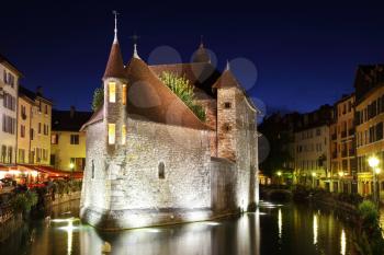 The capital of the Haute-Savoie - Annecy. The main attraction of the city - an ancient fortress-prison on an island in the middle of the river. Fortress beautifully lit and reflected in the dark water
