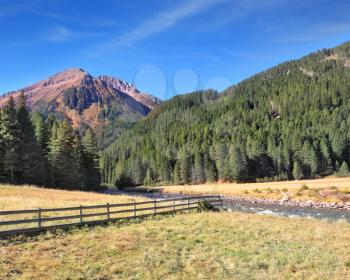 The picturesque mountain valley. Rapid stream, dense coniferous forest and easy farm fence. National Park Krimml waterfalls