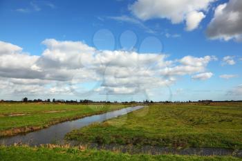 Cloudy skies and coastal grassy plain with channels in Holland