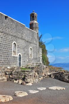 One of the oldest churches in the Sea of Galilee.  Stone wall of gray stone on a smooth slope to the lake water