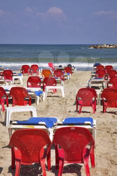Picturesque red chairs and dark blue deck-chairs on a huge sea beach