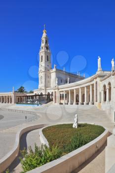 A huge tower and a marble colonnade around the square. The grand memorial and religious complex in the small Portuguese town of Fatima. 