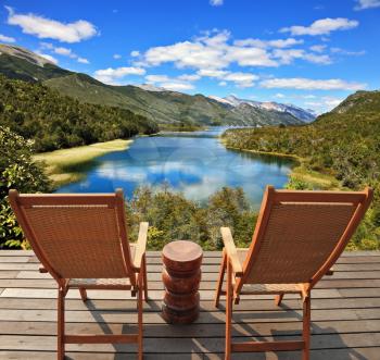 Charming rural idyll. Clouds reflected in the smooth water of the river. A comfortable place to enjoy the beauty of the landscape. Two wooden chairs - on a wooden platform