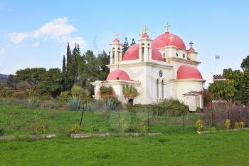 White walls, pink domes and golden crosses the Orthodox Church of the Twelve Apostles. Sunset on the Sea of ​​Galilee.
