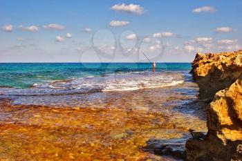 Lonely fisherman on a sunny sea shore 
