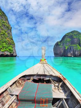 Sea water is emerald green and the islands covered with green plants.  Boat trip on the native boat. Thailand