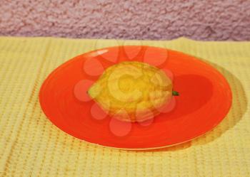 Jewish ritual fruit - etrog on orange plate and yellow napkin