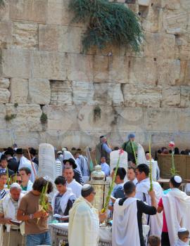 JERUSALEM, ISRAEL - SEPTEMBER 20, 2013:The Western Wall of the Temple in Jerusalem. Many religious Jews in traditional robes tallit gathered for prayer. Morning Sukkot