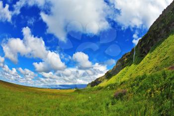 Green meadows and cloud sky. Warm summer days in Iceland