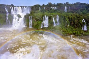  Fantastically spectacular boiling and thundering waterfalls of Iguazu. Waterfalls in Brazil.  Above the water is a picturesque rainbow