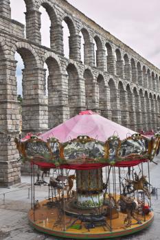 Children's roundabout and ancient aqueduct on the area of Segovia