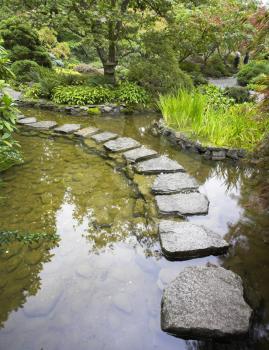  A footpath from stones laid with brick through a fine pond in Japanese garden
