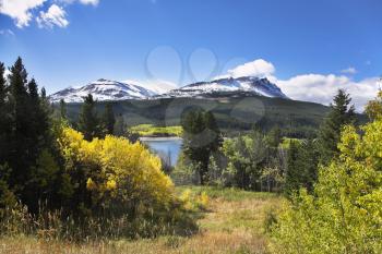 Classical northern landscape - cold lake, mountains with a snow and the turned yellow bushes