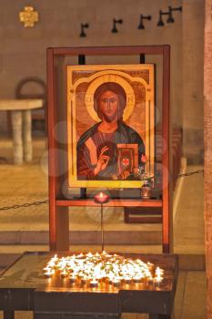 Magnificent old icon of Jesus Christ, and a table with burning candles. The ancient church on the Sea of Galilee