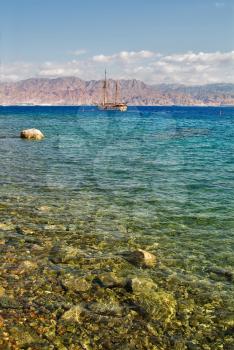 Stones and a sailing yacht in coastal waters of a resort Eilat in Israel