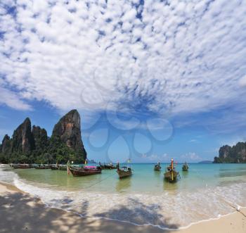 Light cirrus clouds over the warm sea. Picturesque native boat Longtail waiting on the beach the first tourists
The photo is made by a lens the Fish eye

