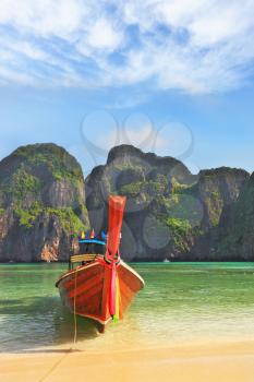 Scenic green islands of Thailand coast. Emerald sea and fine white sand. In sand moored tourist boat, decorated with red silk scarf and a flower wreath