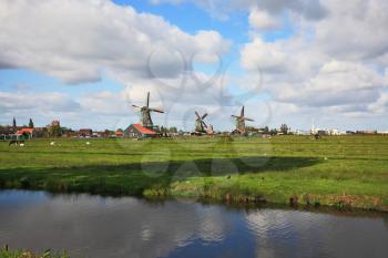 Rural landscape in Holland. Green field, equal coast of the channel with still water and  country symbol - the windmill