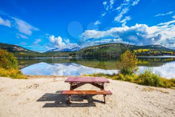 Early morning on cold Pyramid Lake, Jasper National Park. On the shore of the lake -  table and benches for picnic