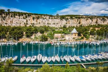 White sailboats moored in rows near the shore. Picturesque small bay - Calanques with turquoise water between Marseille and Cassis