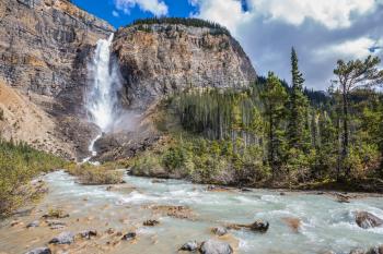Autumn  Takakkaw Falls forms a full-flowing water flow of pearl color. Yoho National Park. Rocky Mountains of Canada