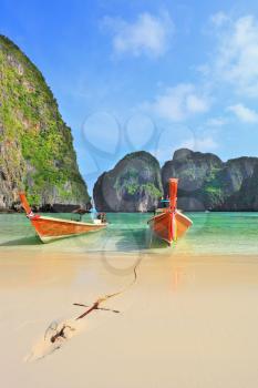 Scenic green islands of Thailand coast. Emerald sea and fine white sand. In sand approached by two tourist boats, decorated with colorful silk scarves and wreaths