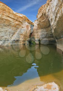 Unique canyon En-Avdat in the Negev desert. Sandstone canyon walls form round bowl. Bowl waterfall reflects the sky