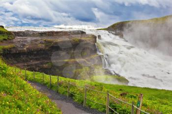 Powerful high-water waterfall in Iceland. For walks and observations on the hillside laid convenient path