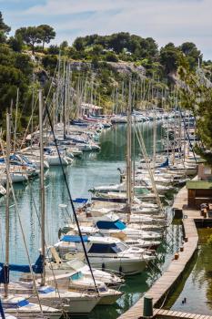 Calanque National Park - small fjords between Marseille and Cassis. White sailboats moored in rows near woody shore. Good weather in May