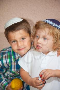 Two beautiful Jewish boy in skull-caps. The elder brother holds a ritual fruit - Etrog. Sukkot