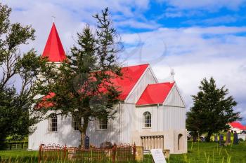 Fancy rural church with red roof on green lawn. Travel to Iceland