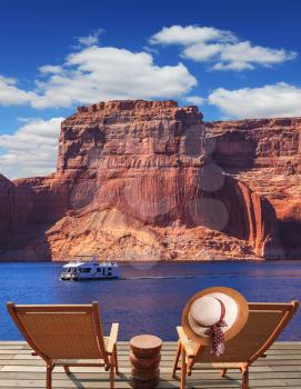 At the stern of the boat are two deck chairs. On the back of one hanging elegant ladies straw hat. Walk to the tourist boat on Lake Powell on the Colorado River