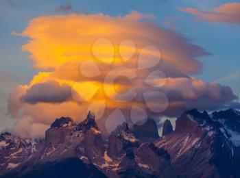  The clouds are illuminated by the sun on the rocks Los Quernos. Incredible sunset in the national park Torres del Paine, Chile