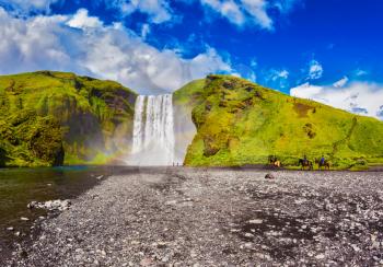 Huge waterfall flowing from under giant glacier. Iceland, waterfall Skogafoss summer, clouds of mist