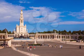 Catholic Cathedral and colonnade in Fatima, Portugal. Believers and tourists walk on the square in front of the cathedral