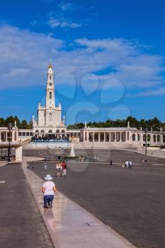 FATIMA, PORTUGAL - SEPTEMBER 9, 2011: The area in front of the Catholic cathedral with tourists and believers. Religious woman in hat kneeling on a specially built track