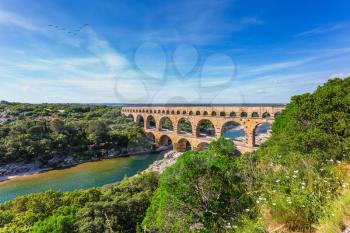 Three-tiered aqueduct Pont du Gard was built in Roman times on the river Gardon. Around the bridge is magnificent natural park. Provence, spring sunny day