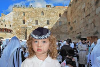 The lovely little boy with long light curls and blue eyes in a knitted skullcap. It costs at the main Jewish shrine - the Western wall of the Temple. Jewish holiday of Sukkot