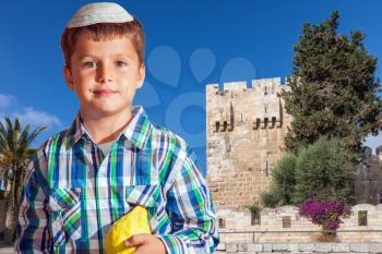  Sukkot in Jerusalem. Charming seven year old boy in white festive skullcap with etrog