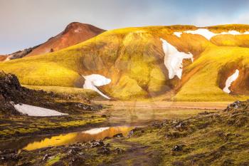 Magic sunrise in the Arctic. The golden light of dawn illuminates the mountains and glaciers national park Landmannalaugar, Iceland