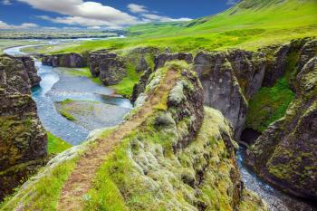  Bizarre shape of cliffs surround the stream with glacial water. The striking canyon in Iceland. The concept of active northern tourism