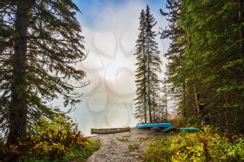  The fishing boat is moored ashore. The Emerald Lake in Yoho National Park. The sun looks through fog