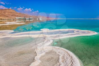 Very salty water in the Dead Sea glows with turquoise light. Summer, Israel. The evaporated salt has developed into fantastic patterns. The concept of ecological and medical tourism