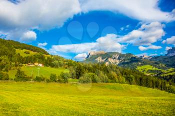 The concept of ecological tourism. Charming green grassy slope of the mountain. Rural pastoral in the Val de Funes, Dolomites. Warm autumn day