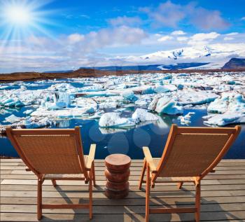 Two wooden deck chairs for admiring the sunset in Jokulsarlon. The concept of extreme northern tourism. Cool northern sun illuminates the Ice Lagoon, Iceland
