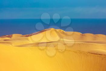 Huge sandy dunes on the ocean coast. Atlantic coast of Namibia, South of Africa. Concept of exotic and extreme tours
