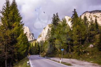 Concept of active and extreme tourism. The road in the Dolomites. Last sunny autumn day on the pass Faltsarego. Rocks covered the sunset rays