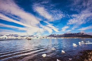 The ice floes and cirrocumulus clouds of lagoon Jokulsarlon, Iceland. Clouds reflected in the water of lagoon. The concept of northern extreme tourism