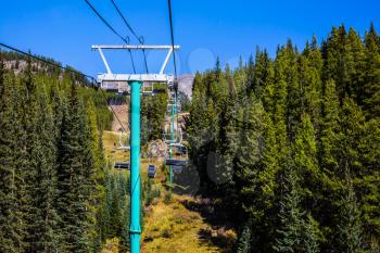 The mountains around the Lake Louise. Suspended cable car over the wooded slopes of the mountains. The Rockies of Canada. Concept of active and ecological tourism